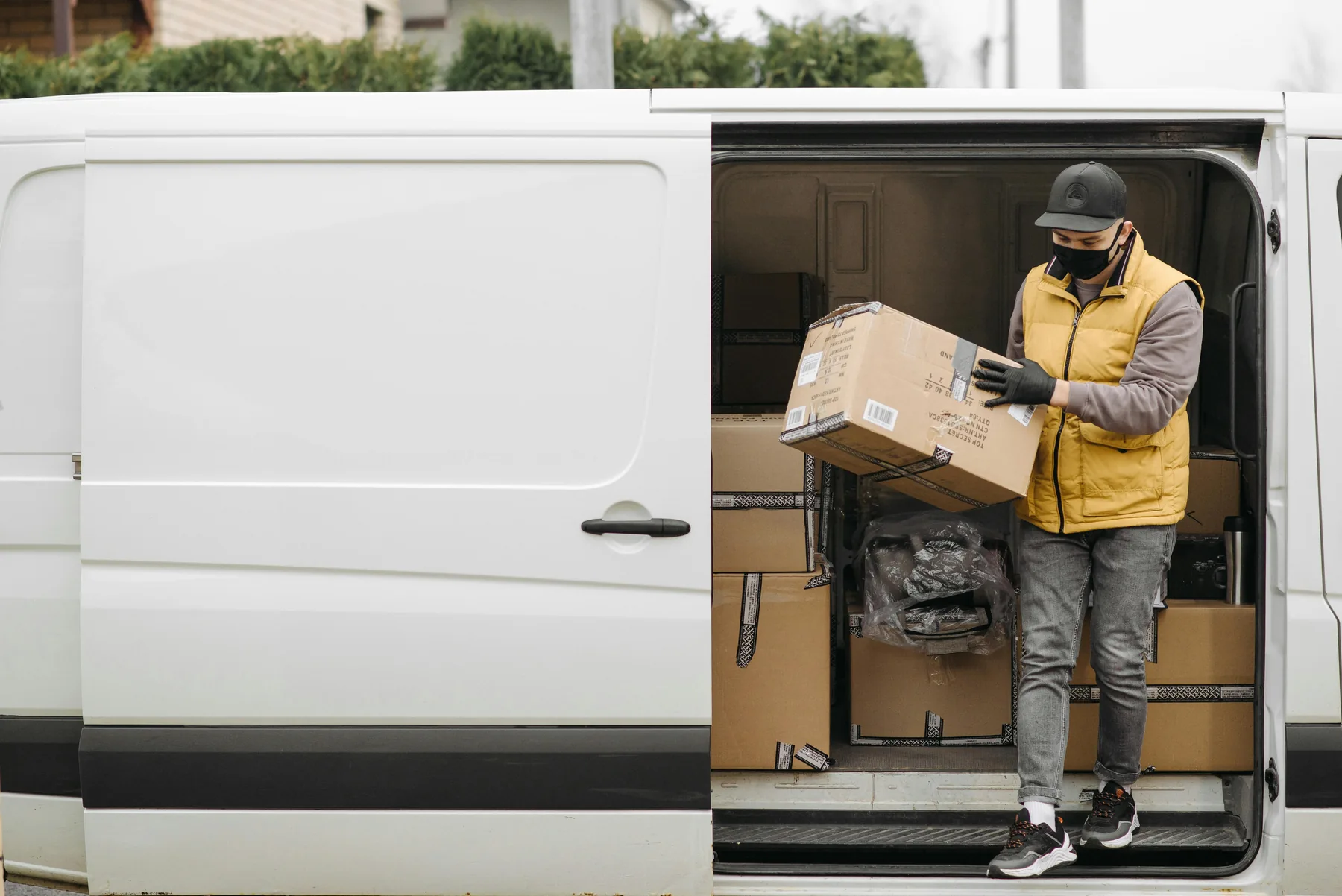 A delivery driver loading a parcel into a white van